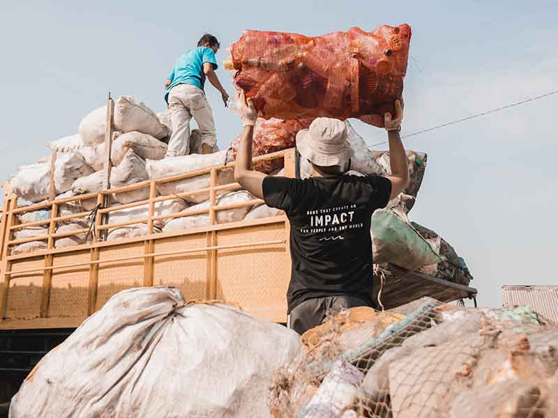 Männer transportieren gesammelten Plastikmüll in großen Säcken