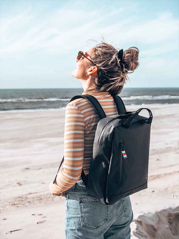 Frau mit GOT BAG Tasche schwarz am Meer