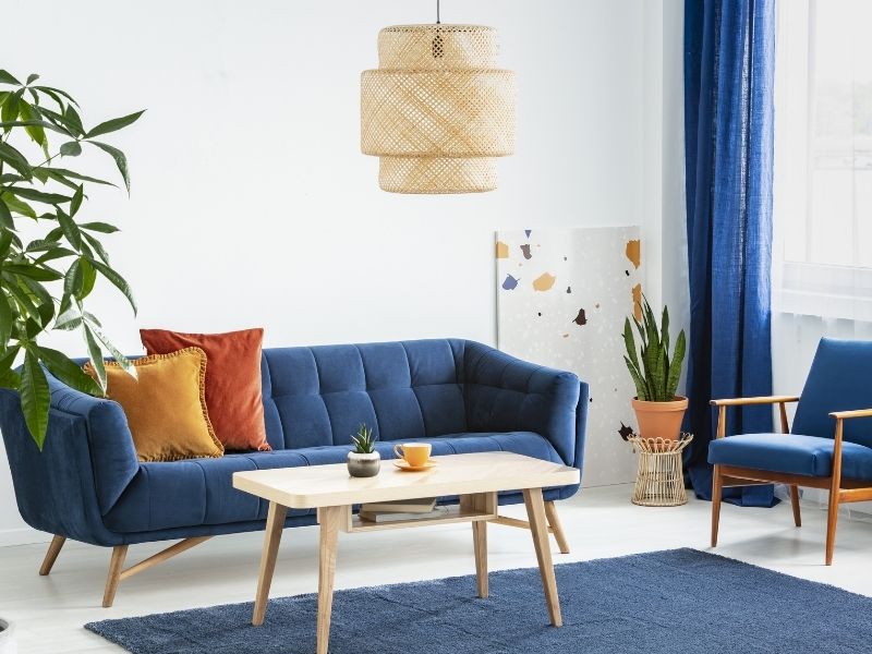 Blaues Sofa mit filigranen Holzbeinen